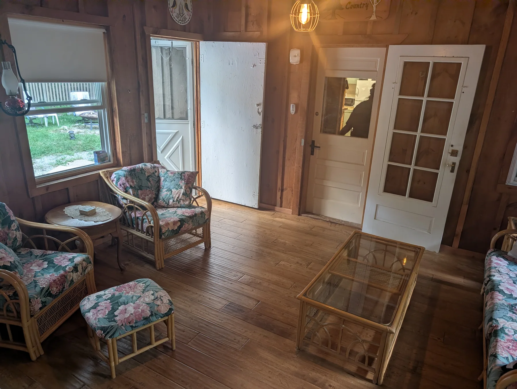 Sunroom with woven seating, a glass-top coffee table, wood walls, and garden-facing windows